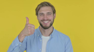 Sarı arka planda Casual genç adam tarafından thumbs up