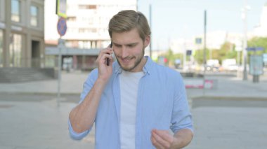 Kızgın Orta yaşlı adam dışarıda telefonla konuşuyor.