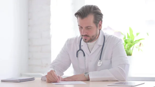 Αρσενικό Γιατρός Γράφοντας Χαρτί Στην Κλινική Ιατρική Έκθεση — Φωτογραφία Αρχείου