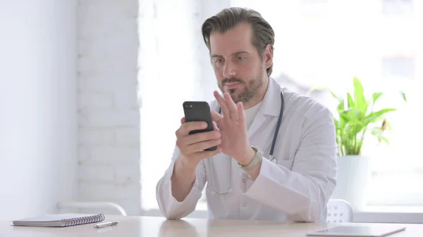 Male Doctor Using Smartphone While Sitting Clinic — ストック写真