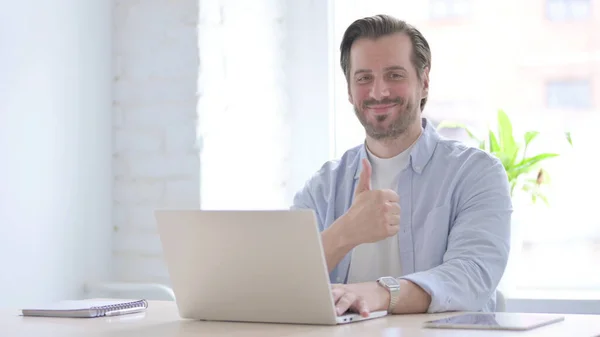 Mature Man Showing Thumbs While Using Laptop — Stockfoto