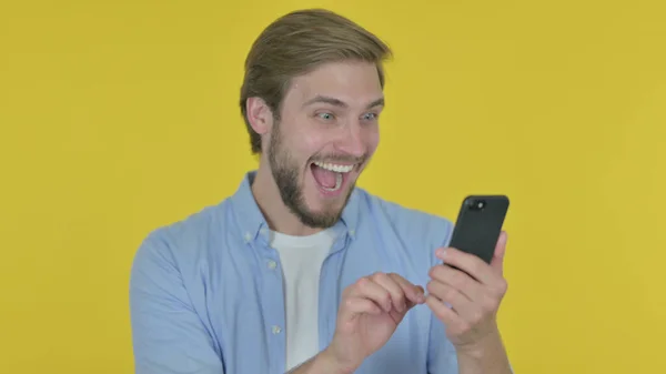 Casual Young Man Celebrating Smartphone Yellow Background — 图库照片