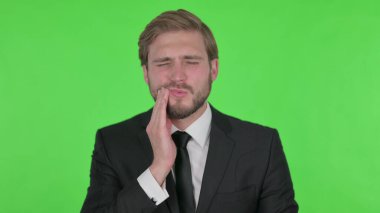 Young Adult Businessman having Toothache on Green Background