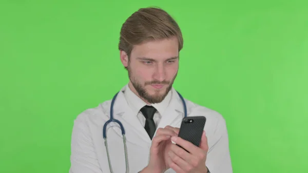 Young Adult Doctor Browsing Smartphone Green Background — Zdjęcie stockowe