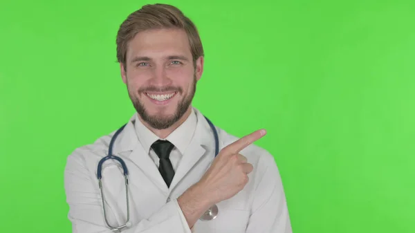 Young Adult Doctor Pointing Side Green Background — Stockfoto
