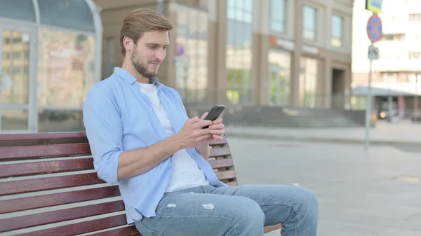 Středověký Muž Procházení Internetu Smartphone Zatímco Sedí Venku Lavičce — Stock fotografie