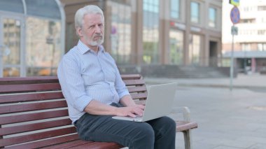 Rejecting Senior Old Man in Denial While using Laptop Sitting Outdoor on Bench