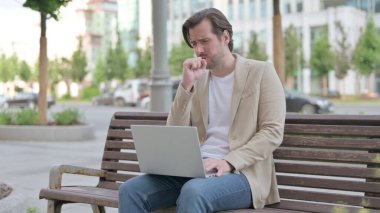 Coughing Man Using Laptop while Sitting on Bench