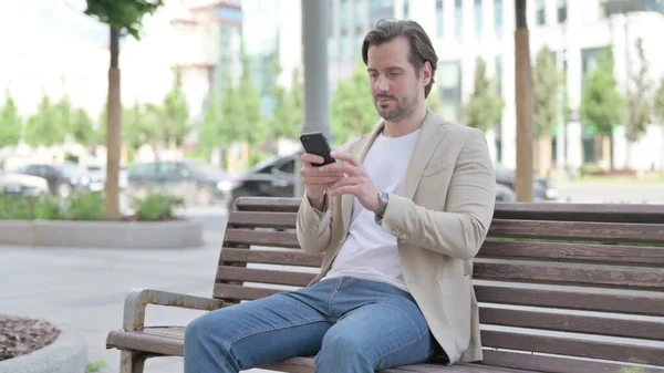 Man Browsing Internet Smartphone While Sitting Bench — Zdjęcie stockowe