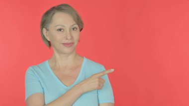 Senior Old Woman Pointing on Side on Red Background