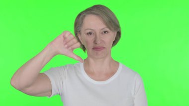 Thumbs Down by Senior Old Woman on Green Background