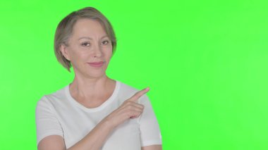 Senior Old Woman Pointing on Side on Green Background