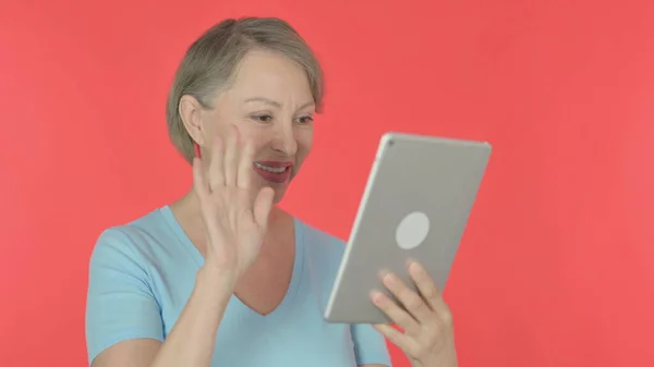 Video Call on Tablet by Senior Old Woman on Red Background