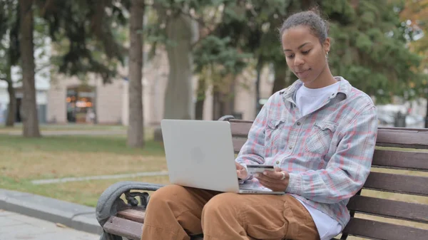 Young African Woman Frustrated by Online Shopping Failure while Sitting Outdoor on Bench