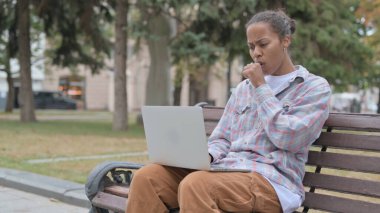 Coughing Young African Woman Using Laptop while Sitting Outdoor on Bench