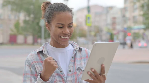 Young African Woman Excited for Success on Tablet Outdoor