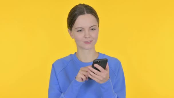 Casual Woman Browsing Smartphone Yellow Background — Stock Video