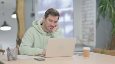 Tired Young Adult Man Sleeping while Working on Laptop