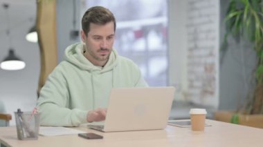 Genç Yetişkin Adam dizüstü bilgisayar kullanırken boyun ağrısı çekiyor