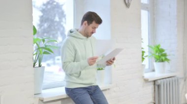 Young Adult Man Using Tablet while Standing Near Window