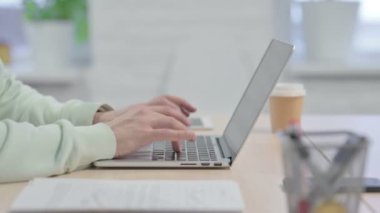 Side View of Young Adult Man Typing on Laptop