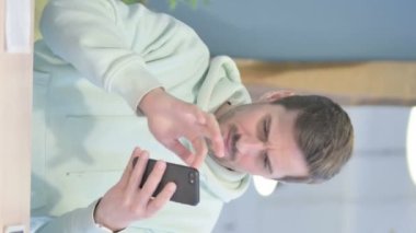 Vertical Video of Young Adult Man Shocked by Loss on Smartphone