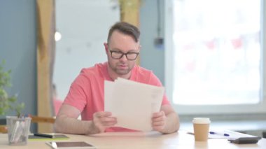 Young Adult Man Reading Documents in Office, Paperwork