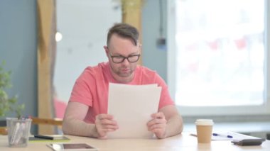 Young Adult Man Reading Documents in Office, Paperwork