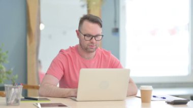 Young Adult Man Shaking Head in Rejection while Working on Laptop