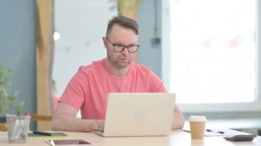 Genç Yetişkin Adam Laptop kullanırken Kameraya Bakıyor