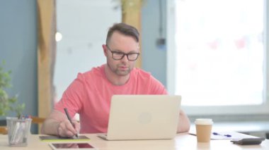 Young Male Graphic Designer Working on Laptop and Graphic Tablet