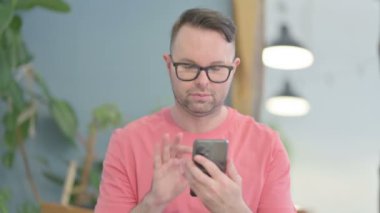 Young Adult Man using Smartphone for Browsing Internet