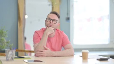 Pensive Young Adult Man Thinking while Sitting at Work