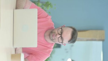 Vertical Video of Senior Old Man Looking at Camera while using Laptop