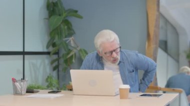 Senior Old Man having Back Pain while Sitting at Work