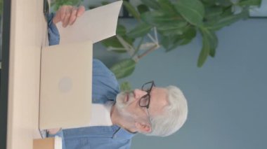 Vertical Video of Senior Old Man Working on Laptop and Documents