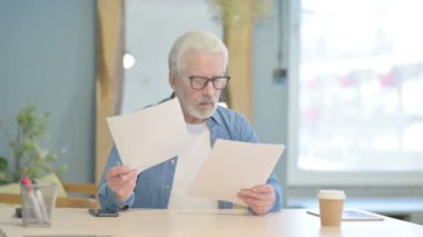 Senior Old Man Celebrating Win while Reading Documents in Office