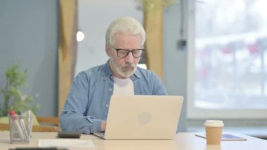 Confident Senior Old Man Looking at Camera while using Laptop