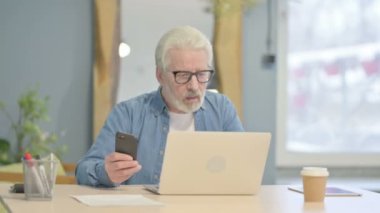 Senior Old Man using Phone and Laptop for Work