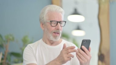 Portrait of Senior Old Man Celebrating Success on Smartphone