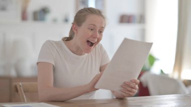 Young Woman Celebrating Success on Document in Office