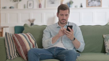 Casual Man using Smartphone on Sofa