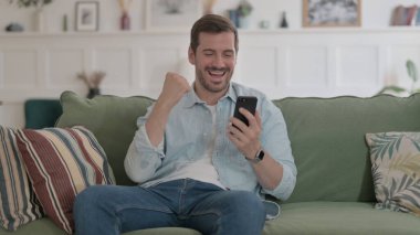 Casual Man having Success on Smartphone at home