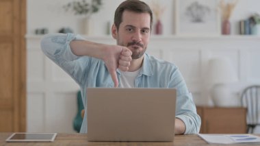 Casual Man Showing Thumbs Down While using Laptop