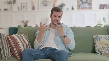 Angry Casual Man Talking on Phone on Sofa