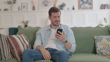Casual Man having Loss on Smartphone at Home