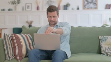 Casual Man Siting on Sofa, Opening Laptop