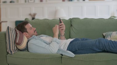 Casual Man using Smartphone while Sleeping in Bed