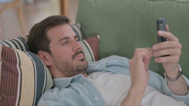 Casual Man using Smartphone while Sleeping in Bed