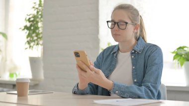 Ofiste akıllı telefon kullanan çekici güzel kadın.